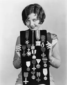 Tokens: Woman holding display of medals