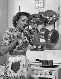 Camerique: Woman in kitchen taste testing her cooking