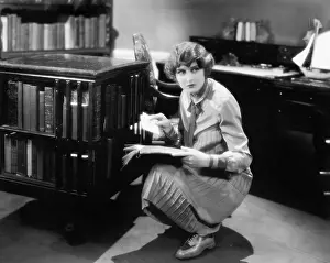 Concealment: Woman kneeling with a book in her library finding a letter