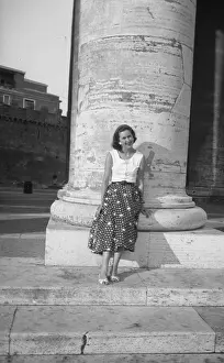 Leans: Woman leans against pillar