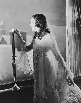 Snug: Woman lighting candle on winter evening