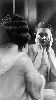 Scrutinising: Woman looking in a dressing table mirror