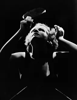 Focused: Woman looking in hand mirror