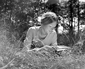 Literate: Woman lying in a field reading a book
