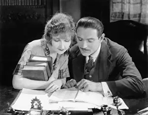 Side By Side: Woman and man sitting together and looking at a book