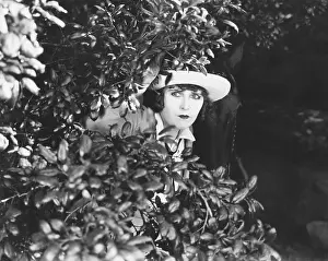 Sincerity: Woman peeking through bushes
