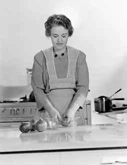 Employ: Woman peeling onions into a bowl in the kitchen