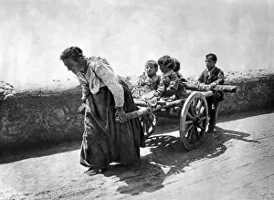 Need: Woman pulling her children in a cart, 1925