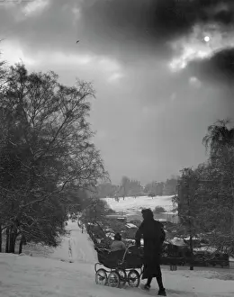 Blanketed: Woman pushing pram through the snow
