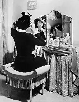 Poise: Woman putting on a hat in front of a dressing table