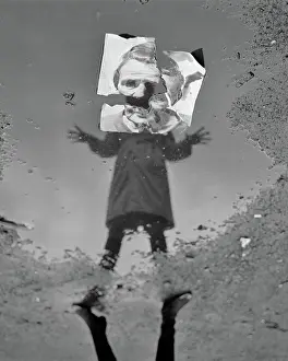 Delusion: Woman in Raincoat Looking into Puddle with Reflection B
