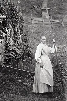Rakes: Woman with a rake with a very long handle. About 1910