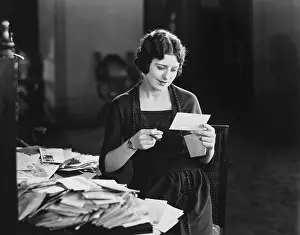 Envelopes: Woman reading letter with pile of mail