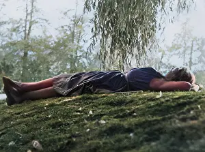 Reclined: Woman relaxing on grass under a tree