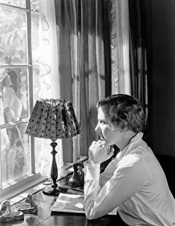 Daydreams: Woman sitting at a desk and looking through a window