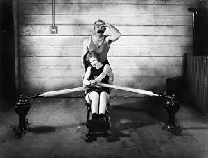 Timid: Woman sitting on a rowing machine with a man behind her