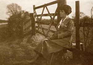 Stile: Woman sitting on a stile by a five-bar gate