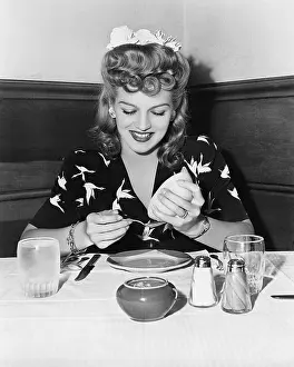 Squeezing: Woman sitting at a table and squeezing a grapefruit
