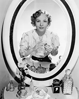 Waist Up: Woman sitting in front of her vanity looking into