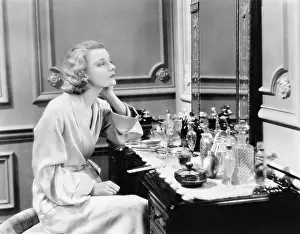 Flacon: Woman sitting at her vanity looking into the mirror