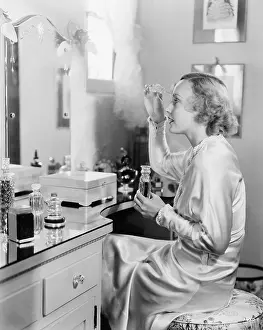 Bedrooms: Woman sitting in front of her vanity putting perfume