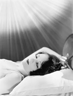 Restful: Woman sleeping in a bed with rays of light shining on her
