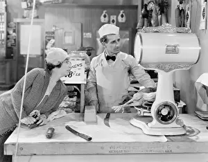 Foodstuff: Woman standing in a butcher store looking at the scale