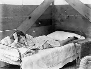 Bunks: Woman stretched out on a cot reading a book