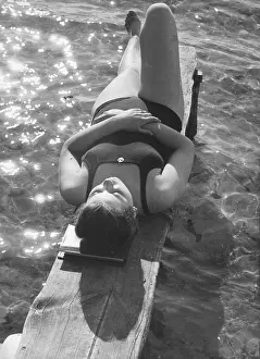 Woman sunbathing on a jetty