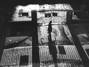 Unease: Woman walking past railings, alone at night