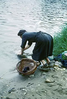 Uncomfortable: Woman washing clothes in a river