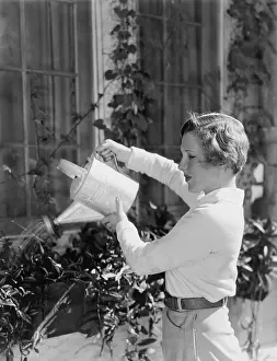 Cultivating: Woman watering plants in window boxes