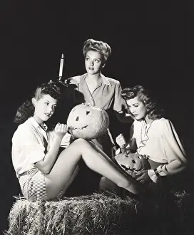 Pumpkins: Three women in a barn carving pumpkins at night