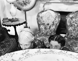 Concealment: Two women hiding behind a table and looking over the edge