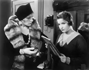 Remorse: Two women looking at a picture in a picture frame