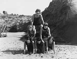 Cooperate: Women making a pyramid on the beach