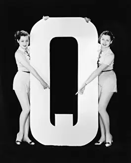 Sameness: Two women pointing at huge letter Q