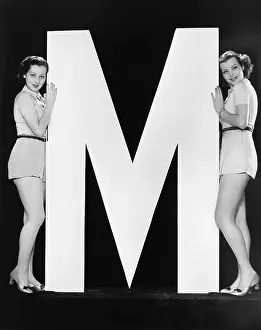 Allure: Two women posing with huge letter M