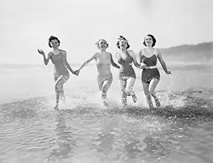 Vigorous: Four women running in water on the beach