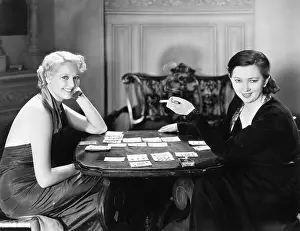 Wagers: Two women sitting together playing cards