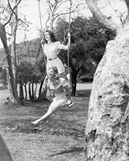 Friendliness: Two women sitting and standing on a swing