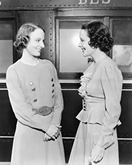 Timid: Two women standing in front of a train and smiling