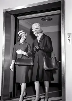 Two Women Stepping Off Elevator Talking Wearing