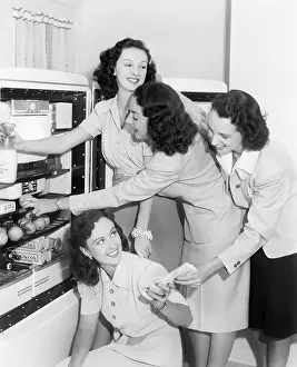 Cooperate: Four women taking things from a refrigerator