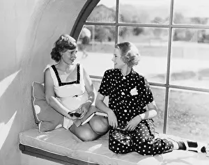 Blonds: Two women in front of a window looking at each other