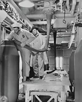 Filling: Workers fill each end of a large bomb with TNT, 1943