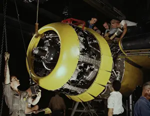 Warplane: Workers mounting motor on a B-25 bomber plane, circa 1942
