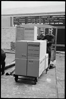 Wheeling: Workers wheeling a trolley of boxes containing