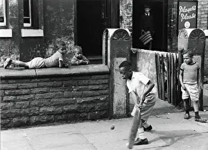 Terraced: Young black boys play cricket on the pavement