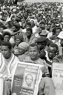 Sizwe: A young black man sits at the front of a crowd